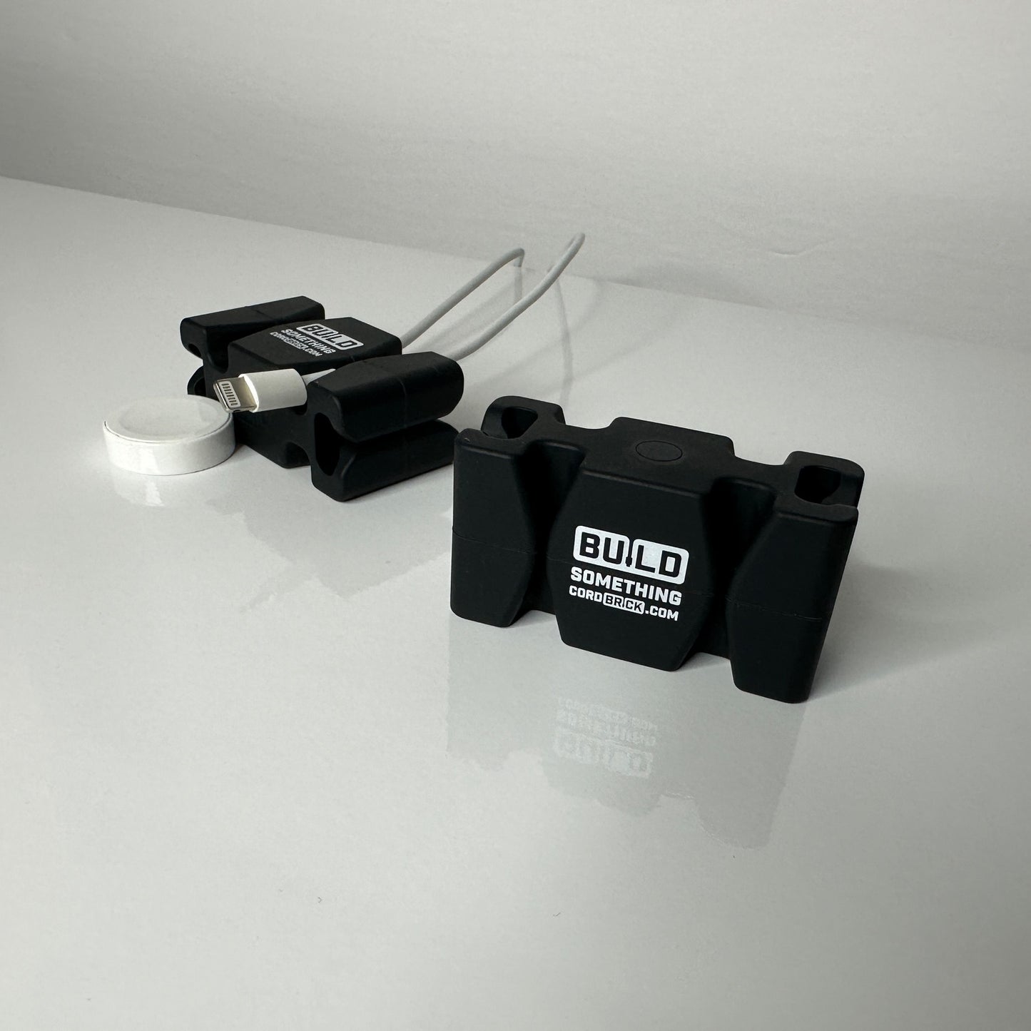 Black Promo CordBricks holding cords on a white desktop